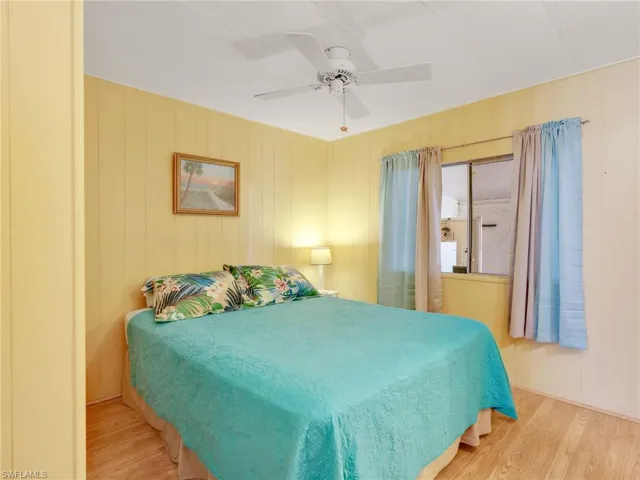 Bedroom featuring wood finished floors, a ceiling fan, and wooden walls