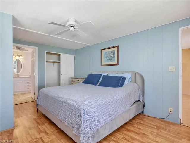 Bedroom with wood finished floors, a closet, a ceiling fan, and connected bathroom
