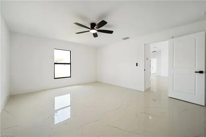 Spacious room featuring light-colored tile flooring, a ceiling fan, and a window providing natural light