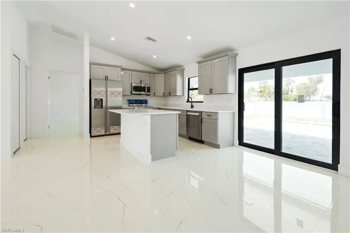 Modern kitchen featuring light gray cabinetry, stainless steel appliances, a center island, and white countertops
