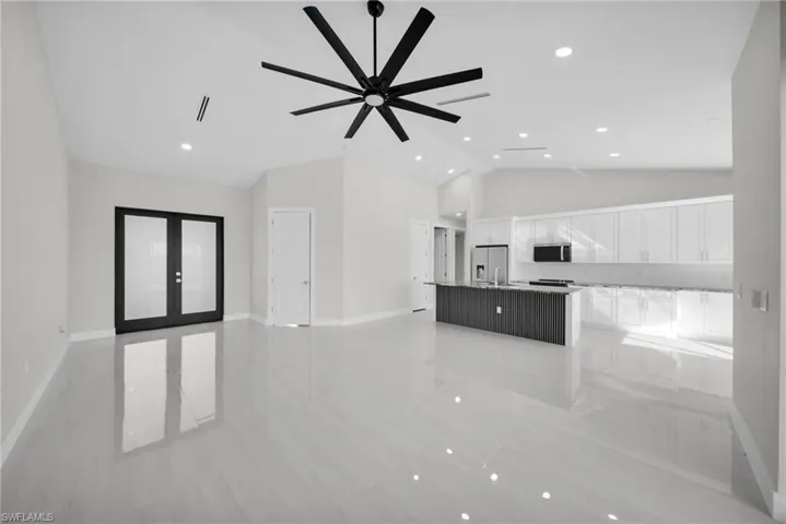Unfurnished living room with high vaulted ceiling, french doors, recessed lighting, and ceiling fan