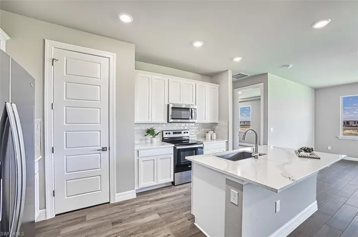 Kitchen featuring white cabinets, appliances with stainless steel finishes, and sink