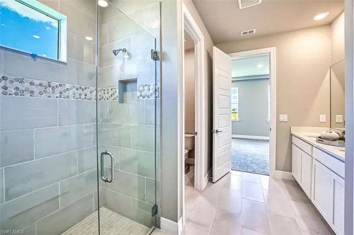 Bathroom with a bidet, toilet, tile flooring, a shower with door, and vanity