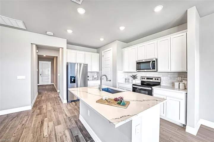 Kitchen with an island with sink, sink, tasteful backsplash, and appliances with stainless steel finishes