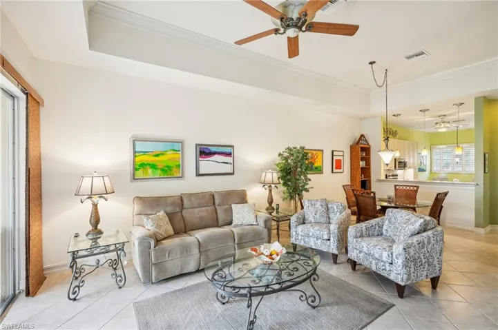 Tiled living room with a tray ceiling, ceiling fan and crown molding