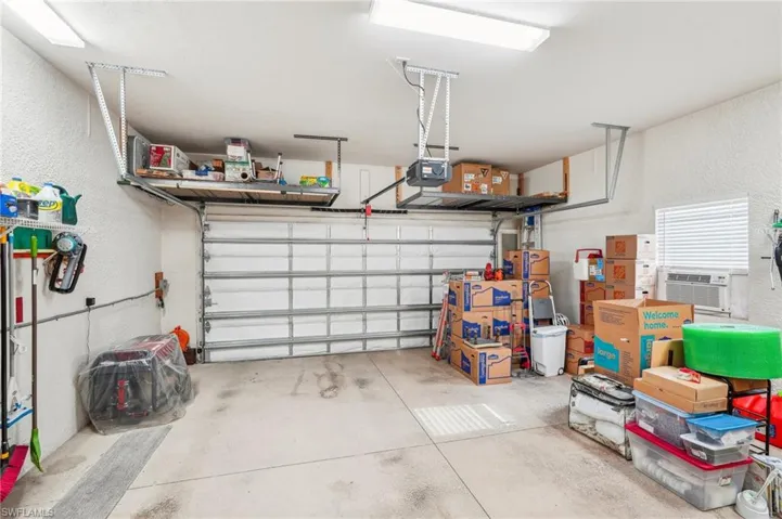 Garage featuring newer garage impact door, workshop, over head storage and attic access