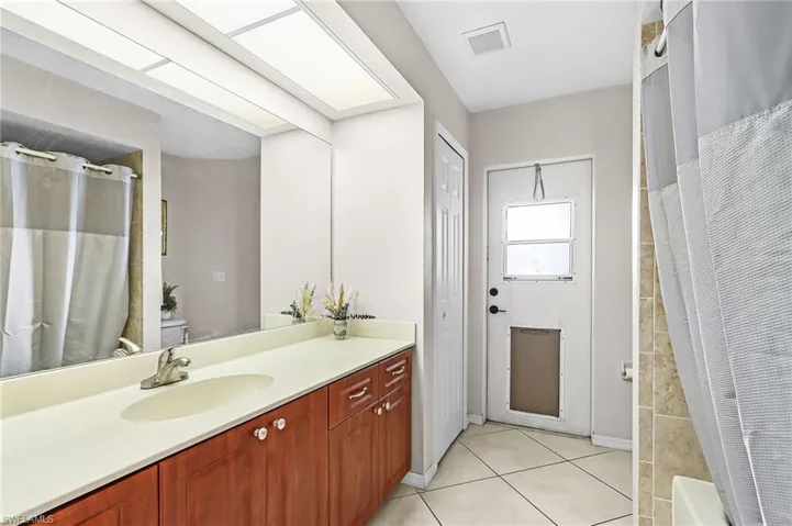Bathroom with vanity, a closet, and light tile patterned flooring