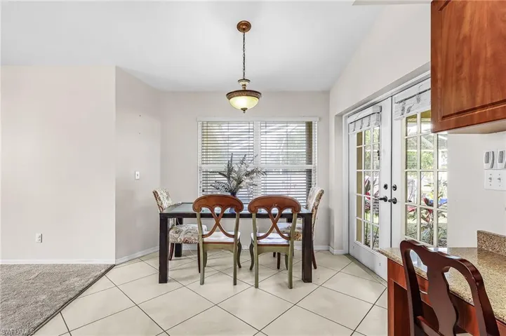Dining space featuring french doors, vaulted ceiling, and light tile patterned floors