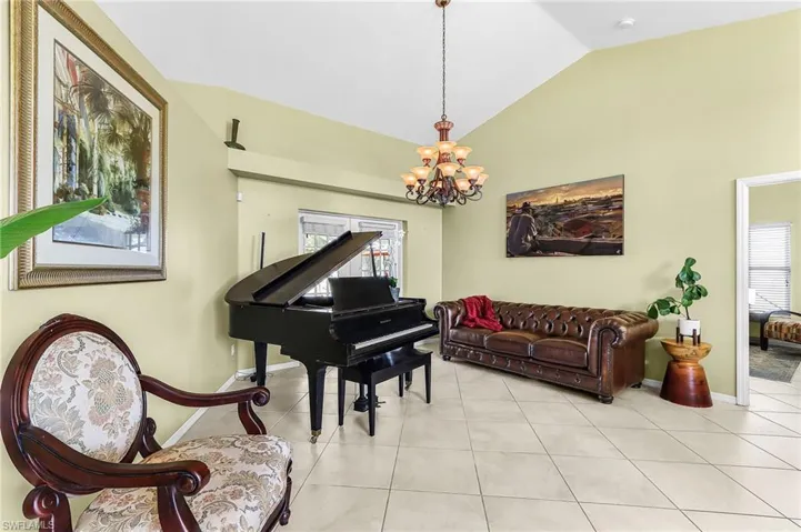 Sitting room with vaulted ceiling, light tile patterned floors, and hanging lights
