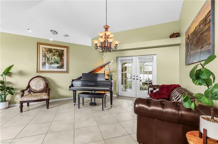 Living area with french doors, hanging lights, and light tile patterned flooring