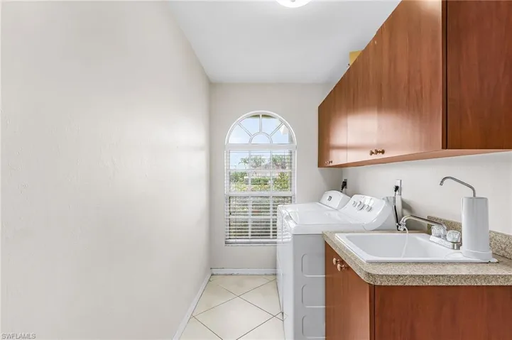 Laundry room with cabinet space, independent washer and dryer, and light tile patterned floors