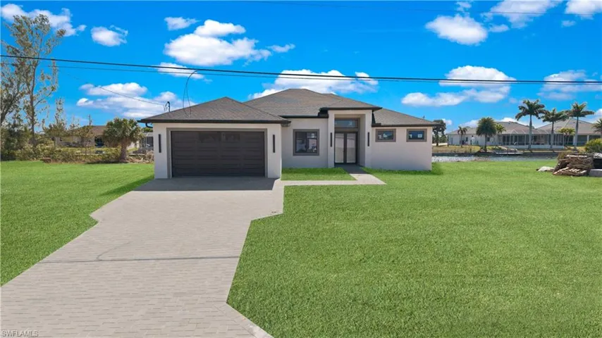 Prairie-style home featuring a front yard, stucco siding, decorative driveway, a garage, and a residential view