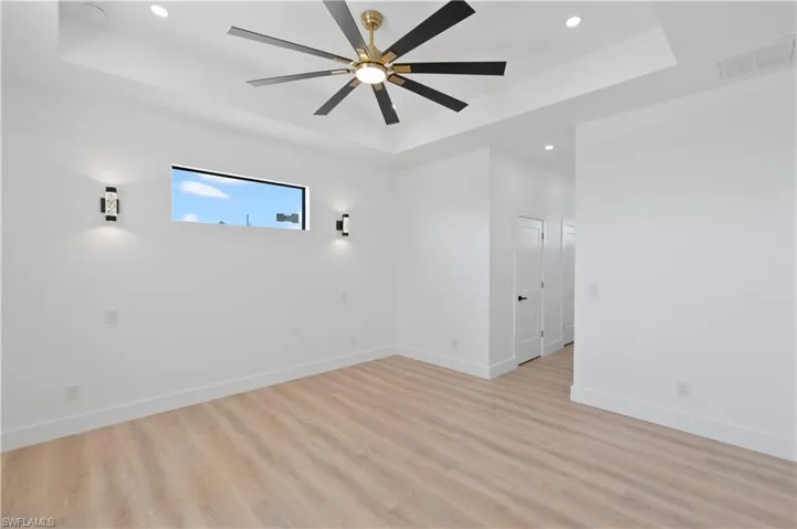 Spare room featuring recessed lighting, a raised ceiling, light wood finished floors, and ceiling fan