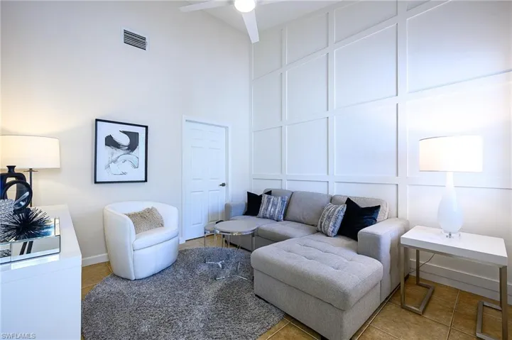 Den area/bedroom with a custom made decorative wall, a high ceiling, and a updated ceiling fan