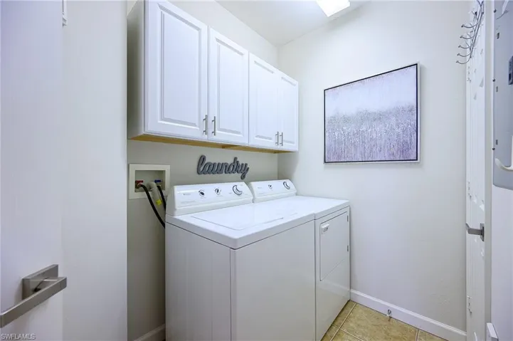 Washroom featuring cabinet space, independent washer and dryer, and light tile patterned floors