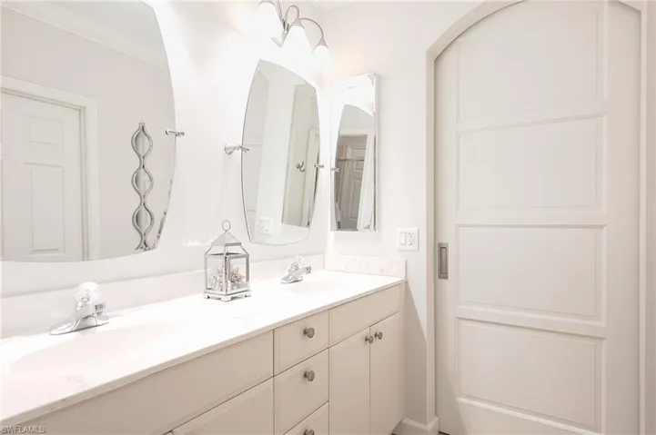 Master Bathroom featuring double vanity and crown molding with updated mirrors and lighting