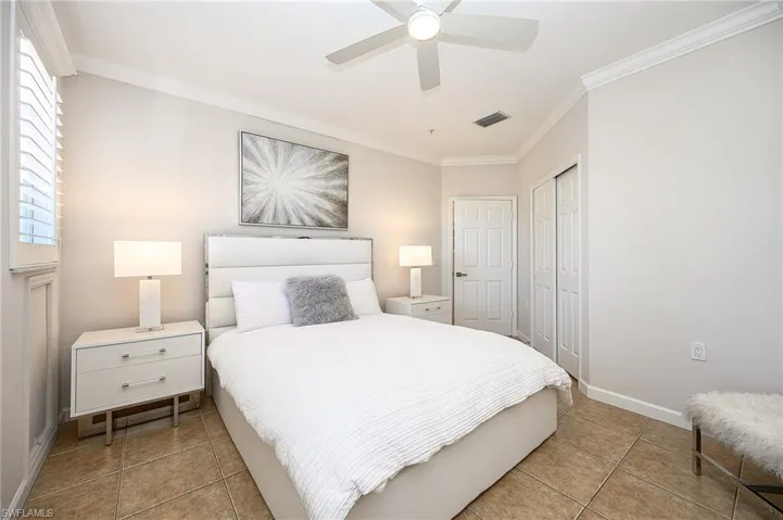 Bedroom featuring ornamental molding, a ceiling fan, a closet, and light tile patterned floors