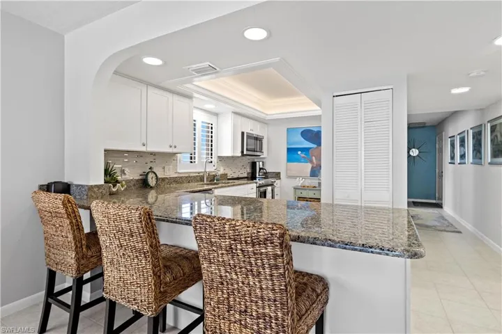 Kitchen with a kitchen breakfast bar, kitchen peninsula, white cabinets, and stainless steel appliances