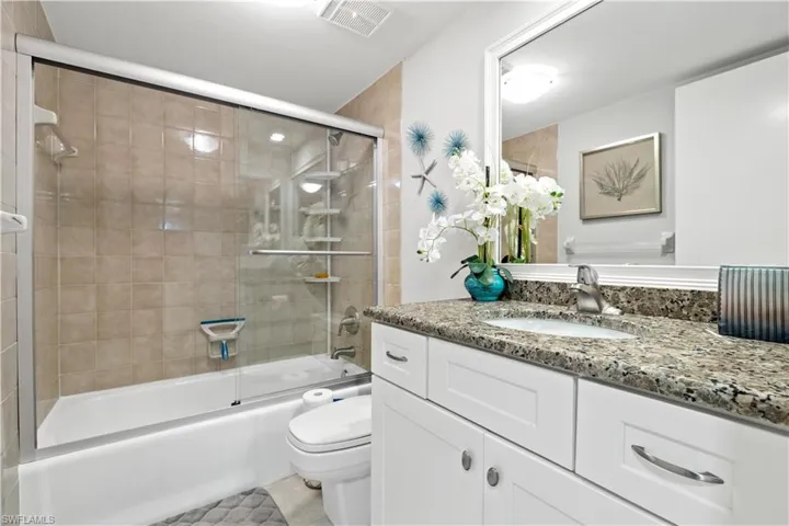 Full bathroom featuring tile patterned floors, vanity, combined bath / shower with glass door, and toilet