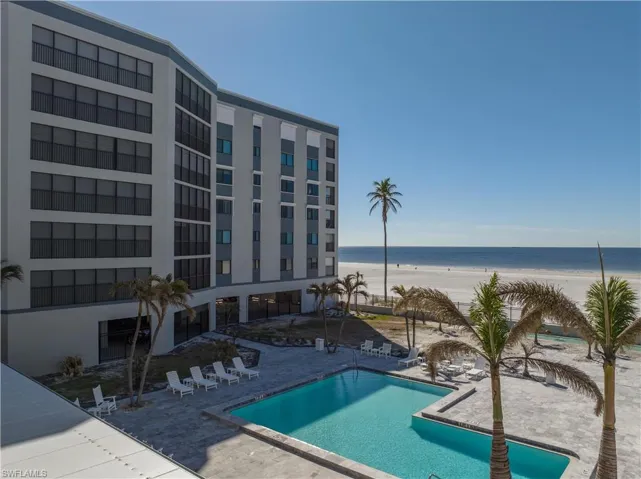 View of pool with a patio area, a water view, and a view of the beach