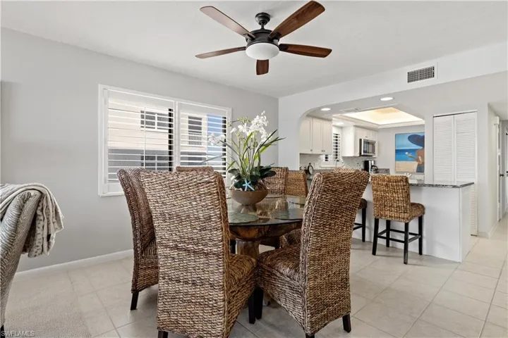 Tiled dining space with a tray ceiling and ceiling fan