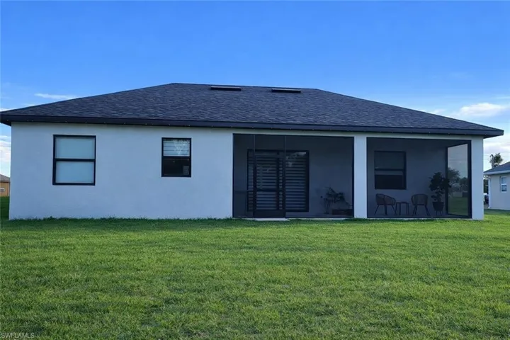 Rear view of house featuring a shingled roof, a yard, stucco siding, and a sunroom