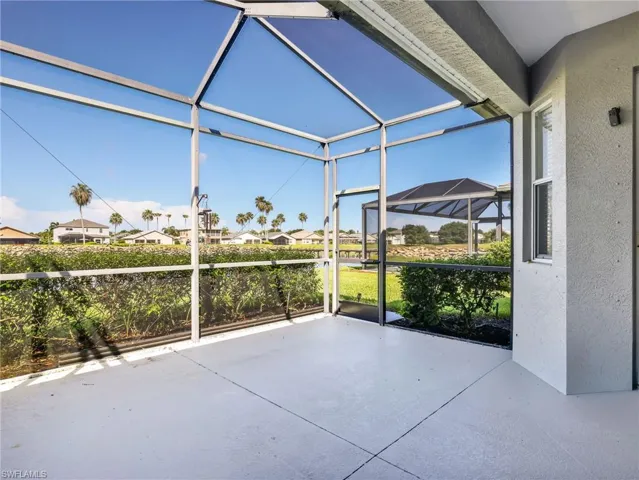 Spacious screened patio featuring a light-toned concrete floor, white frame enclosure, and a screened door