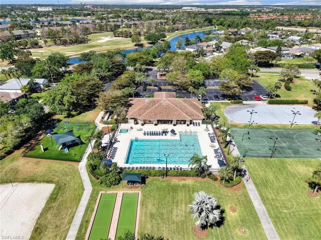 Community clubhouse with a swimming pool, adjacent recreational courts, bocce ball courts, and a sand volleyball court
