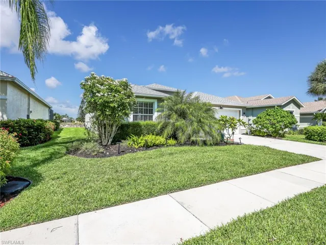 Front exterior with a manicured lawn, established landscaping, concrete sidewalk, and a multi-car driveway