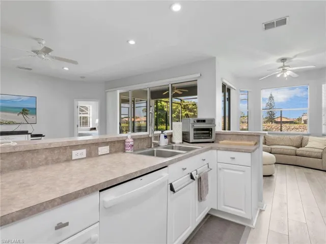Kitchen featuring a double basin sink, white cabinetry, and light-toned countertops