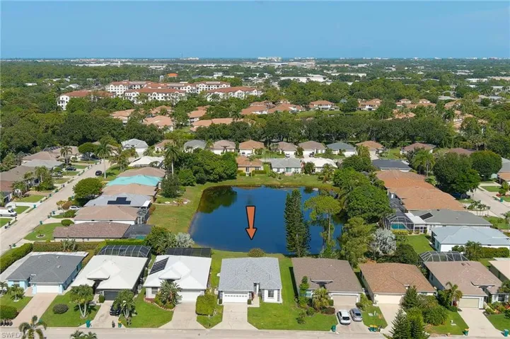 Aerial perspective showcasing a residential community with a central pond