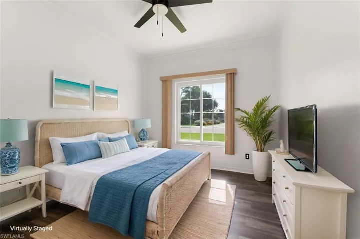 Spacious room featuring wood-finish flooring, a ceiling fan, crown molding, a large window, and white walls
