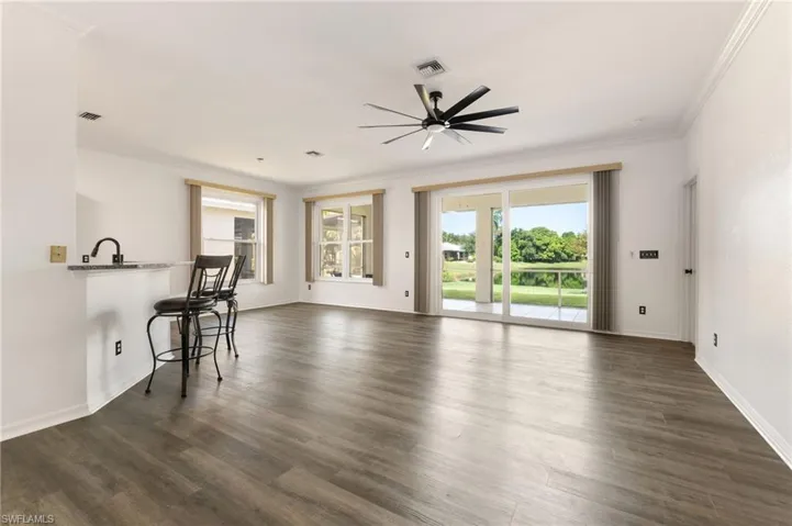 Spacious open-concept interior featuring wood-finish flooring, crown molding, and a modern ceiling fan