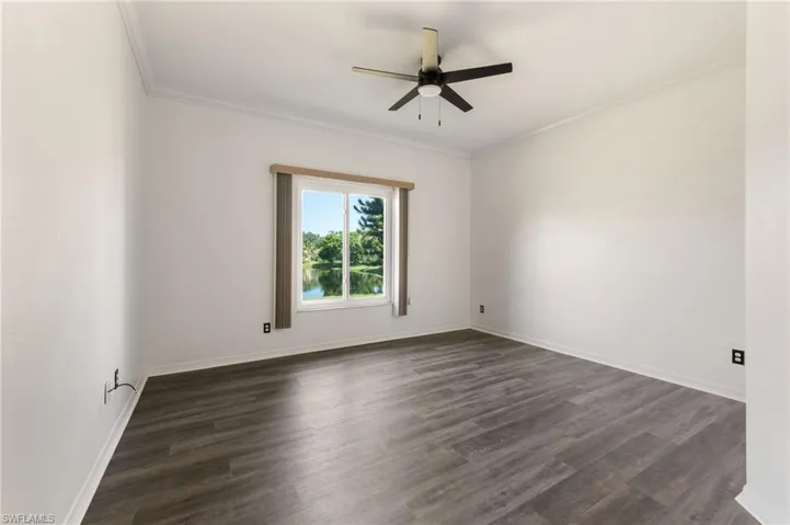 Spacious room featuring wood-finish flooring, crisp white walls, and a contemporary ceiling fan