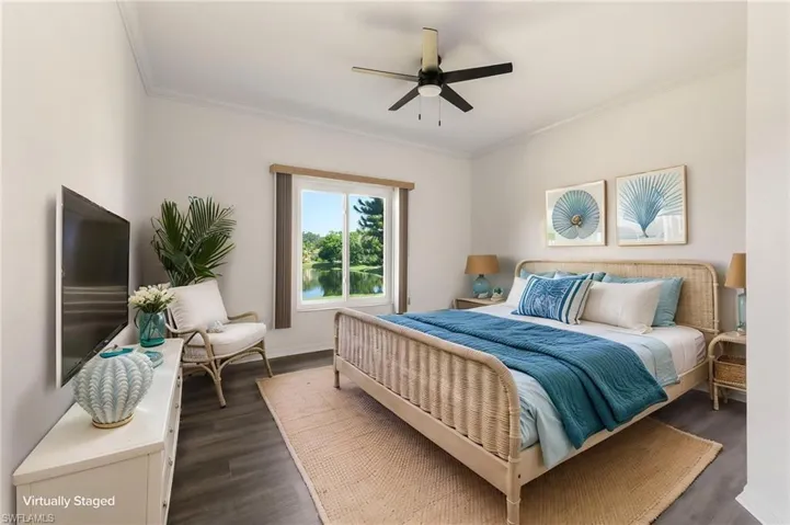 Bedroom featuring wood-finish flooring, a ceiling fan, and a large window overlooking a body of water with trees