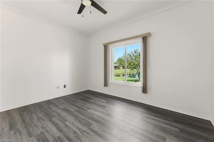 Bright interior space featuring a window with a water feature, wood-finish flooring, a ceiling fan, crown molding, and white baseboards