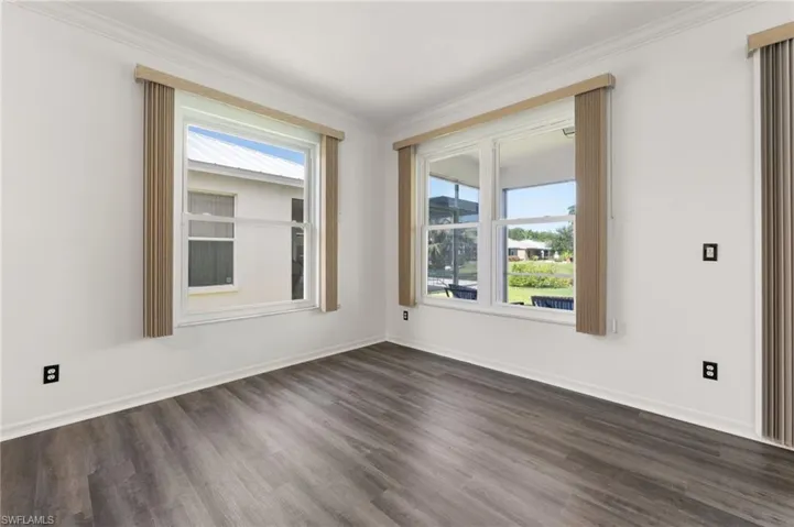 Bright room featuring wood-finish flooring, white walls, and crown molding