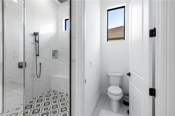 Full bathroom with a marble finish shower, marble look tile flooring, and healthy amount of natural light