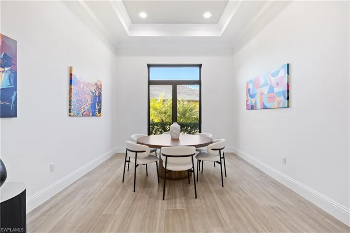 Dining space with light wood-style floors, a raised ceiling, and ornamental molding