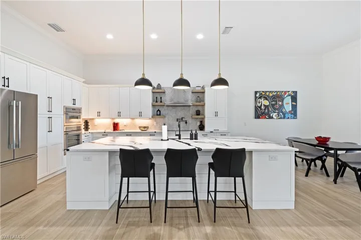 Kitchen with pendant lighting, open shelves, stainless steel appliances, a spacious island, and crown molding