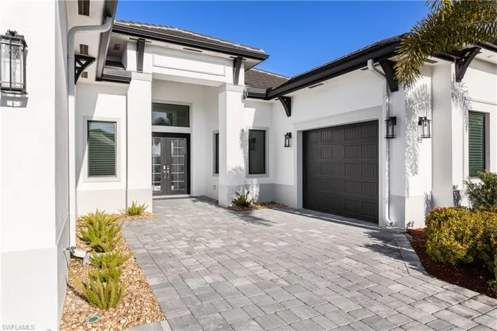 View of exterior entry featuring french doors, stucco siding, driveway, and a tile roof