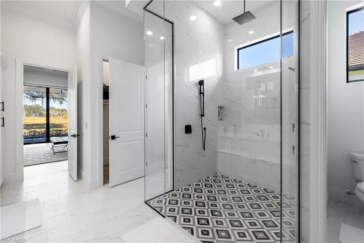Bathroom featuring light marble finish flooring, a marble finish shower, and a spacious closet