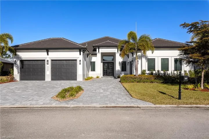 View of front of house with decorative driveway, stucco siding, a front yard, a garage, and a tiled roof