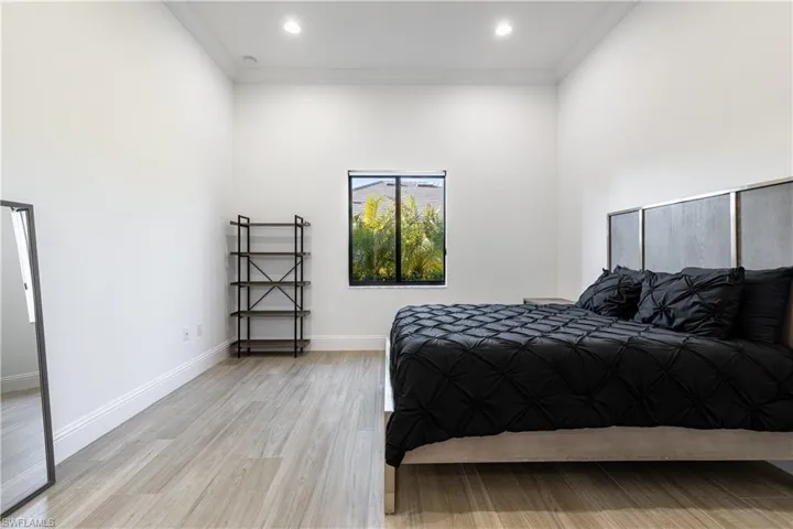 Bedroom featuring light wood-type flooring, crown molding, and recessed lighting
