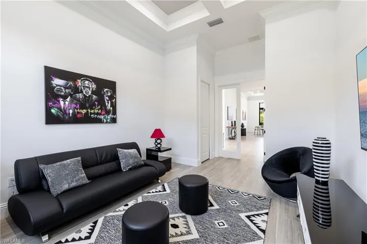 Living room with light wood-style flooring, crown molding, and a high ceiling