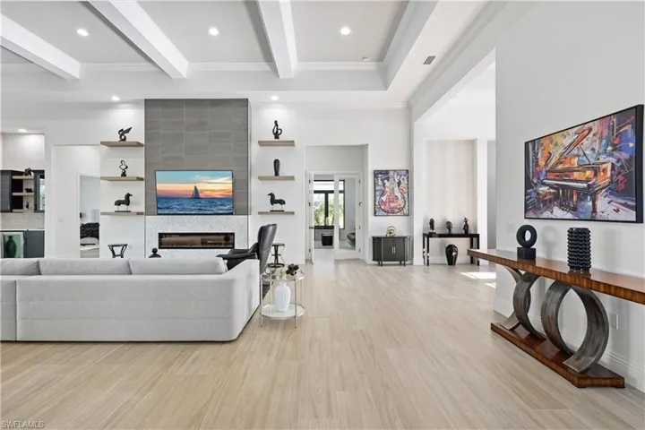 Living room with light wood-type flooring, wine cooler, a fireplace, crown molding, and recessed lighting