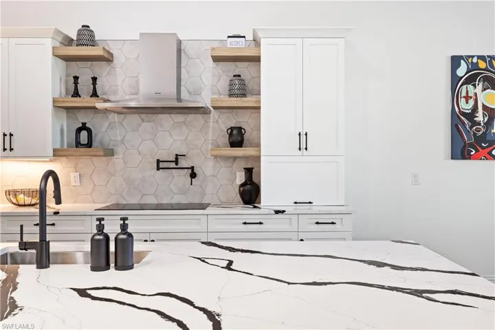 Kitchen featuring open shelves, decorative backsplash, white cabinetry, light stone counters, and black electric stovetop
