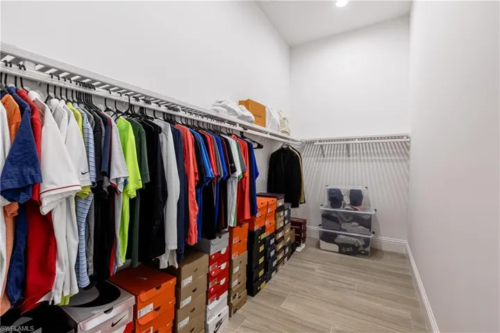 Walk in closet with light wood-style floors and a high ceiling