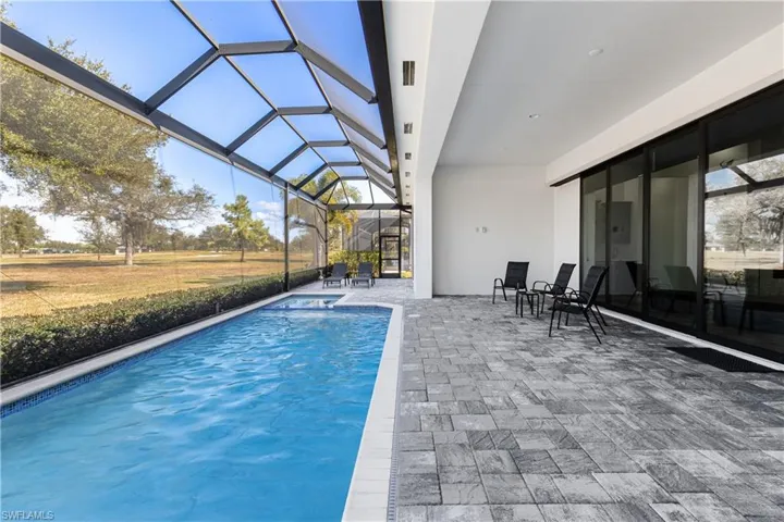 Swimming pool with a sunroom, glass enclosure, and a patio area