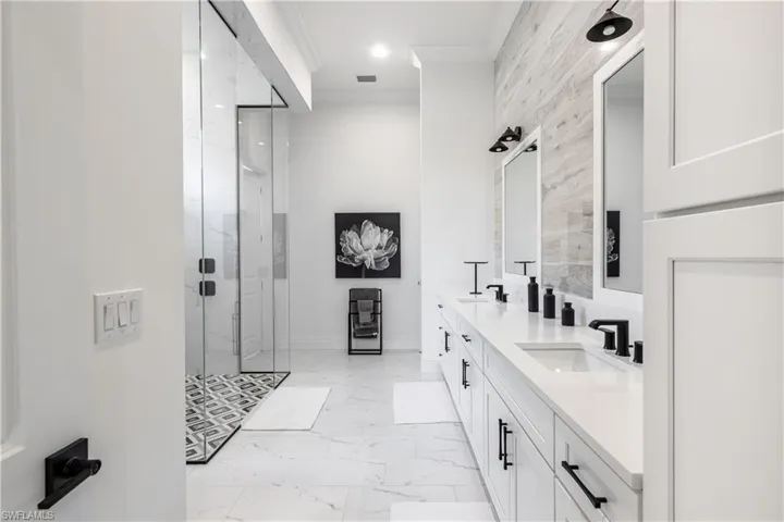 Bathroom featuring crown molding, double vanity, a marble finish shower, recessed lighting, and light marble finish flooring